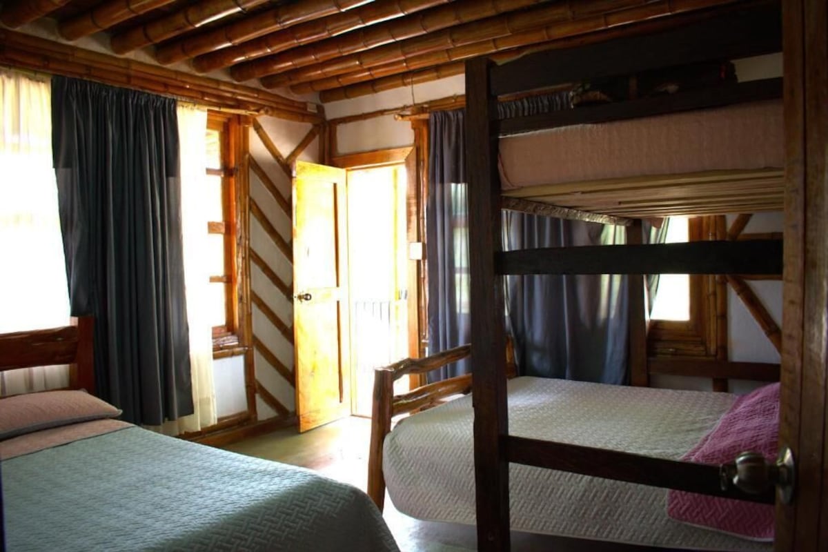 A room with a bunk bed, a wooden chair, and a door leading to another room.