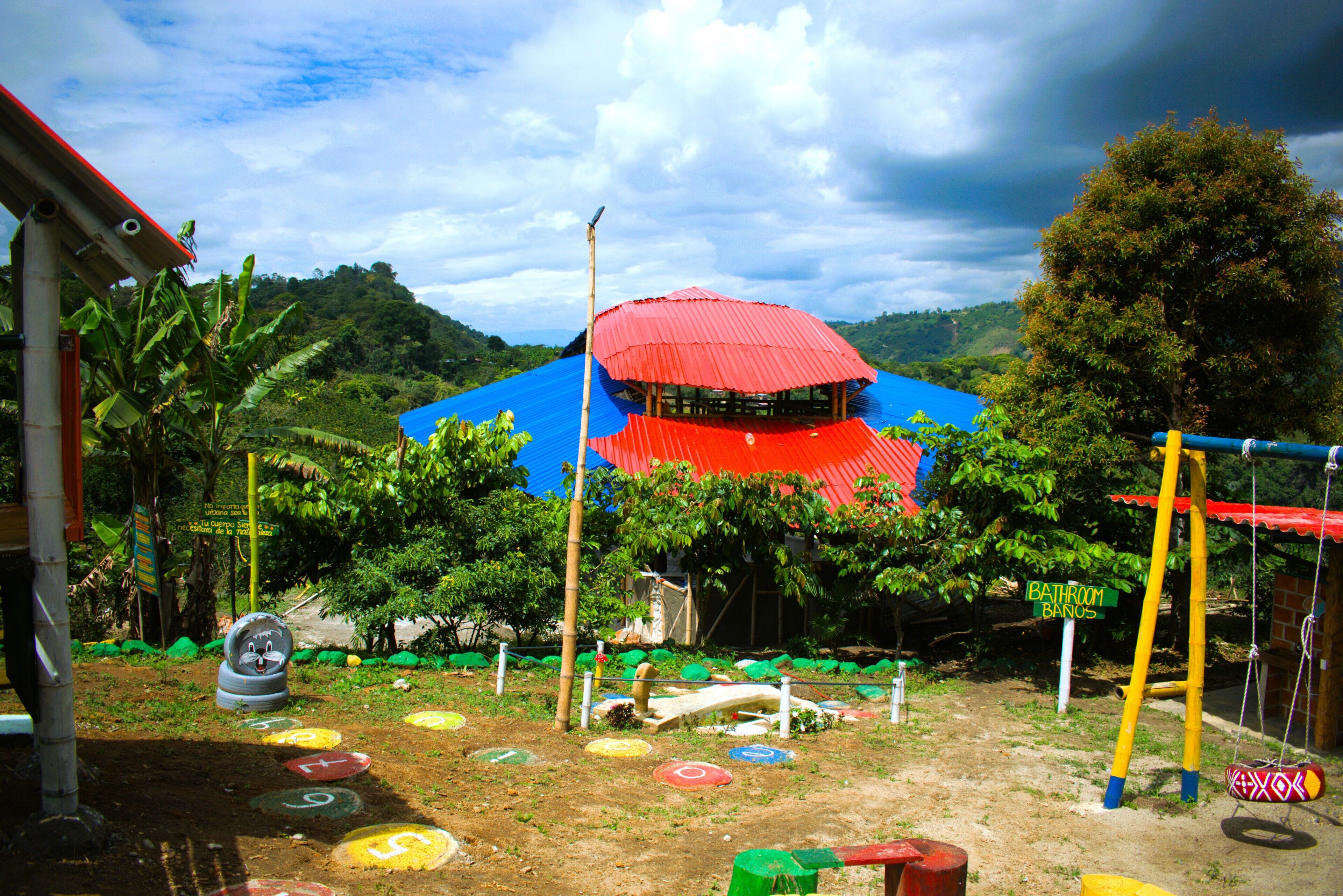 Un parque infantil con juegos de colores y una estructura de techo rojo.