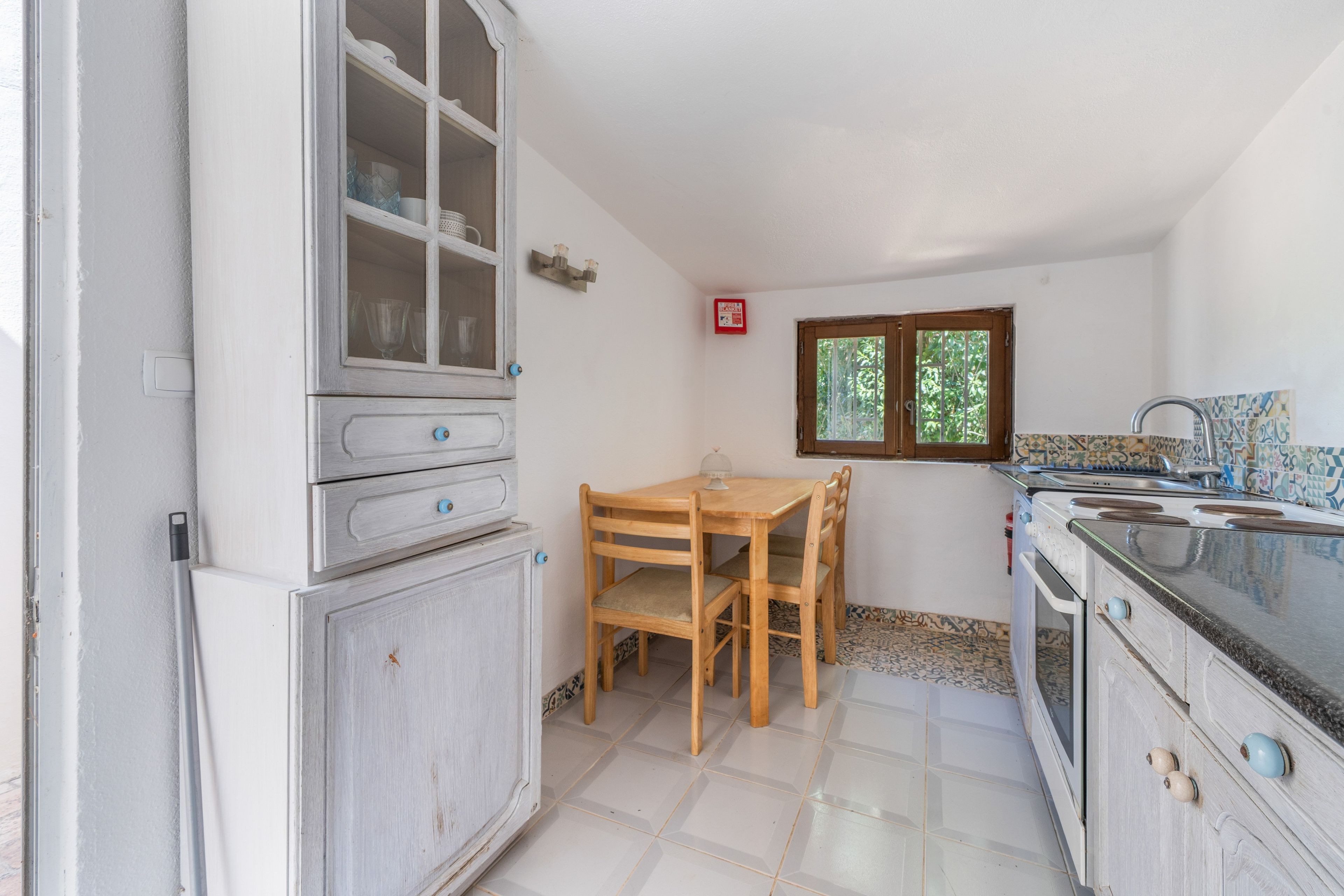 Una cucina con tavolo e sedie, un fornello e pensili.