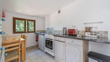 Eine kleine Küche mit Esstisch, Herd und Toaster.