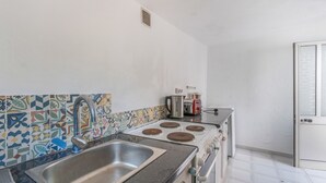 Una cocina con lavamanos, estufa y salpicadero de azulejos.