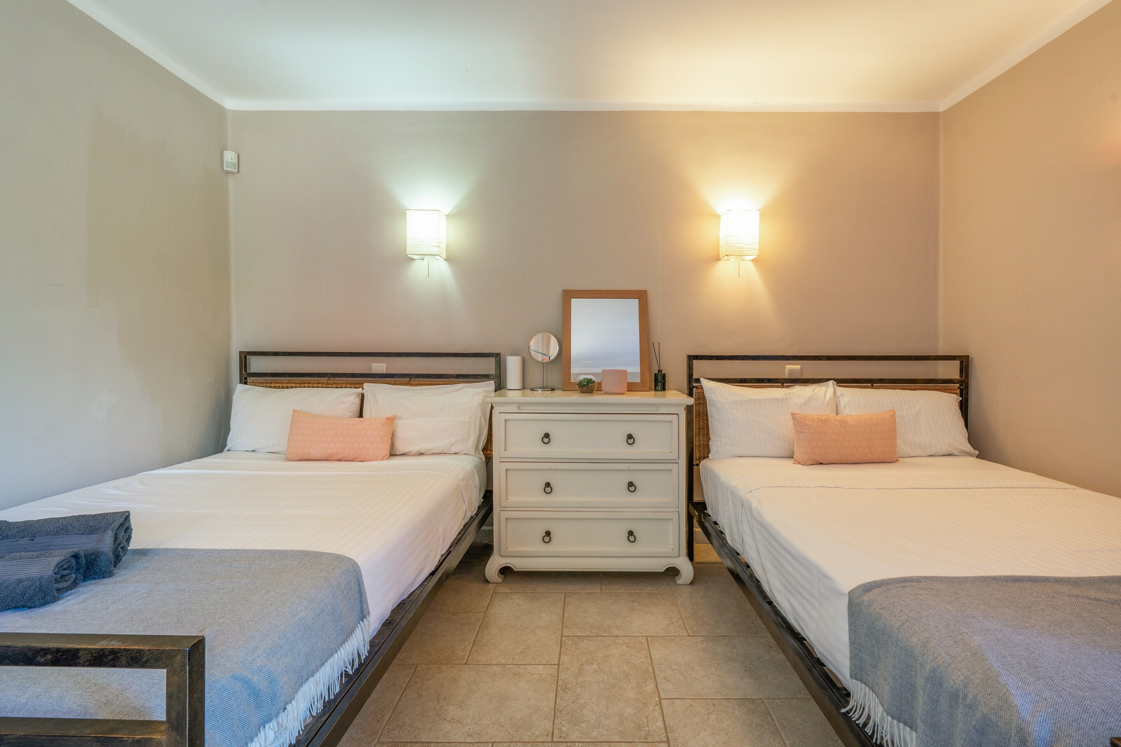 Una camera d'albergo con due letti, una cassettiera e luci a parete.