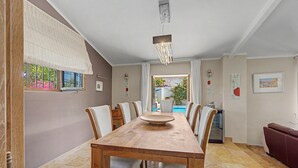 Un comedor con una mesa de madera, sillas y vista a una piscina.
