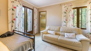 Una habitación con cama, sofá y ventana con cortinas estampadas.
