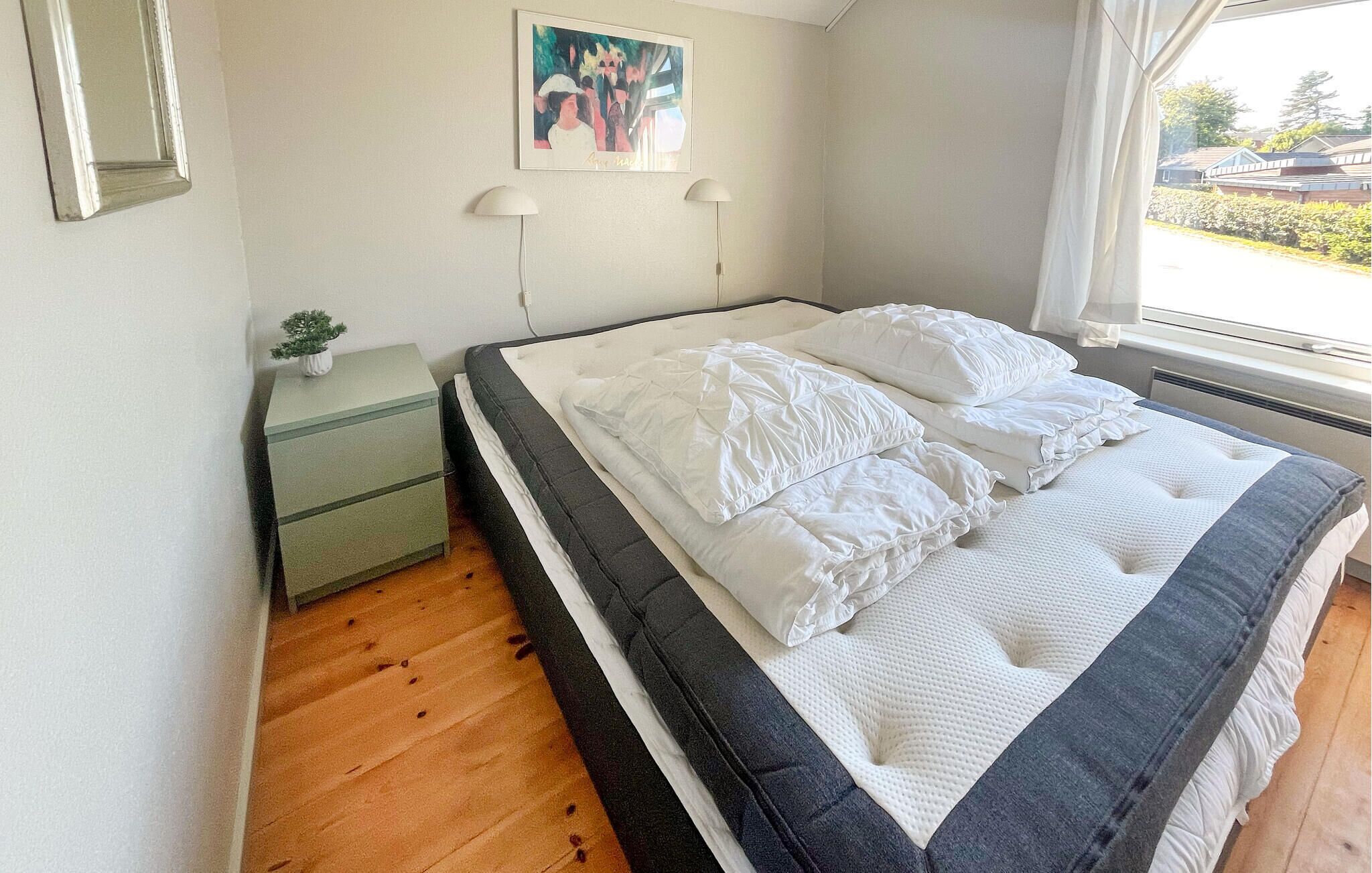 Una camera da letto con un letto, un comodino, una lampada e un quadro appeso al muro.
