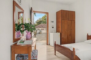 Ein Schlafzimmer mit Holzschrank, Bett, Schreibtisch mit Spiegel und Blumentöpfen.