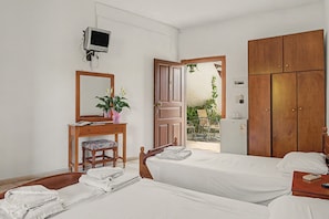 Ein Hotelzimmer mit zwei Betten, einem Schreibtisch mit Spiegel, einem Fernseher und einem Kleiderschrank.