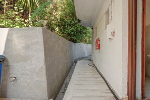 A narrow concrete pathway leading to a building entrance with a fire extinguisher mounted on the wall. - Room 'Orama 24' with Sea View, Wi-Fi and Air Conditioning (Εύβοια)