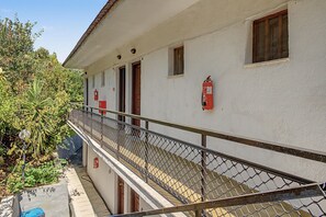 Ein Gebäude mit weißer Fassade, einem Metallgeländer und einem an der Wand befestigten Feuerlöscher.