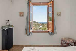 A bedroom with a large window, a bed, a chair, and a radiator. - Room 'Orama 29' with Sea View, Wi-Fi and Air Conditioning (Εύβοια)