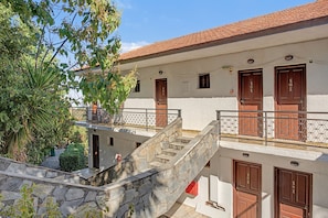 Ein Gebäude mit mehreren Eingängen, einer Steintreppe und einem Balkon mit Metallgitter.