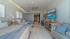 Ein Hotelzimmer mit zwei Betten, einem Sofa, einem Fernseher und einem Deckenventilator.