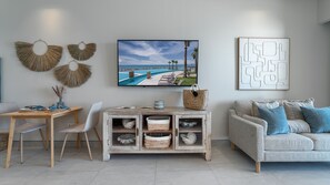 Een moderne woonkamer met uitzicht op het zwembad, een houten eettafel, een grijze bank en decoratieve wandkunst.