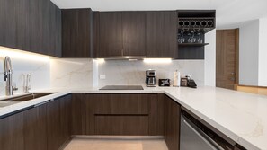 A modern kitchen with dark wood cabinets, a white marble countertop, a built-in wine rack, and a coffee machine. - One 1702 Penthouse: Star Wars Luxury Penthouse (Puerto Peñasco)