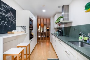 Una cocina moderna con armarios blancos, un lavamanos de acero inoxidable y una pizarra con escritura.