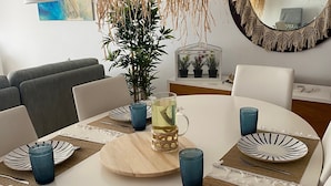 Ett matbord dukat med tallrikar, glas och en kanna, omgivet av stolar.