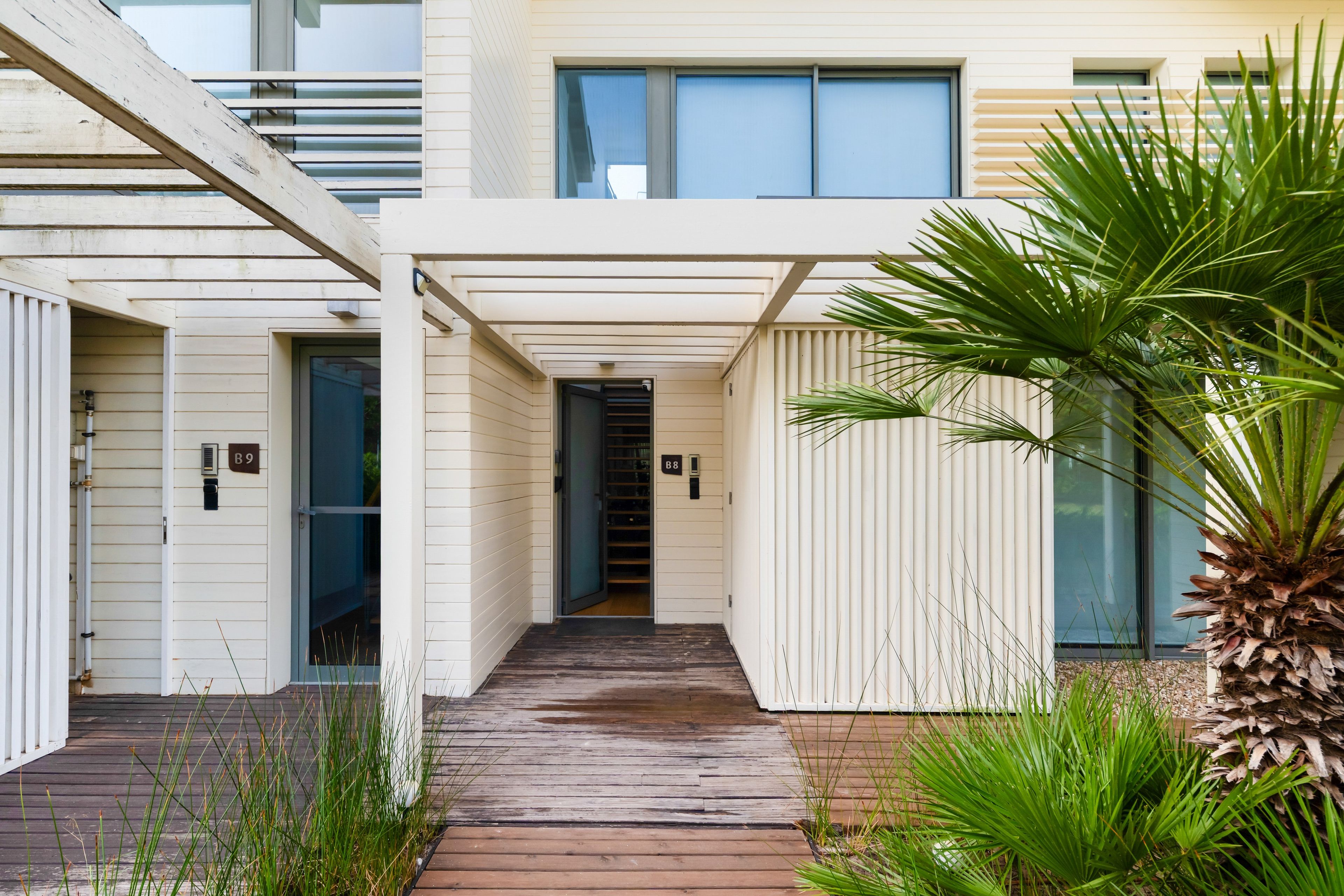 A modern building with a covered walkway leading to a door marked B9.