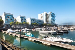 A marina with various boats docked, a wooden pier, and modern buildings in the background. - Holiday Home 'Tróia - Amazing Places' with Wi-Fi and Air Conditioning (Grândola)