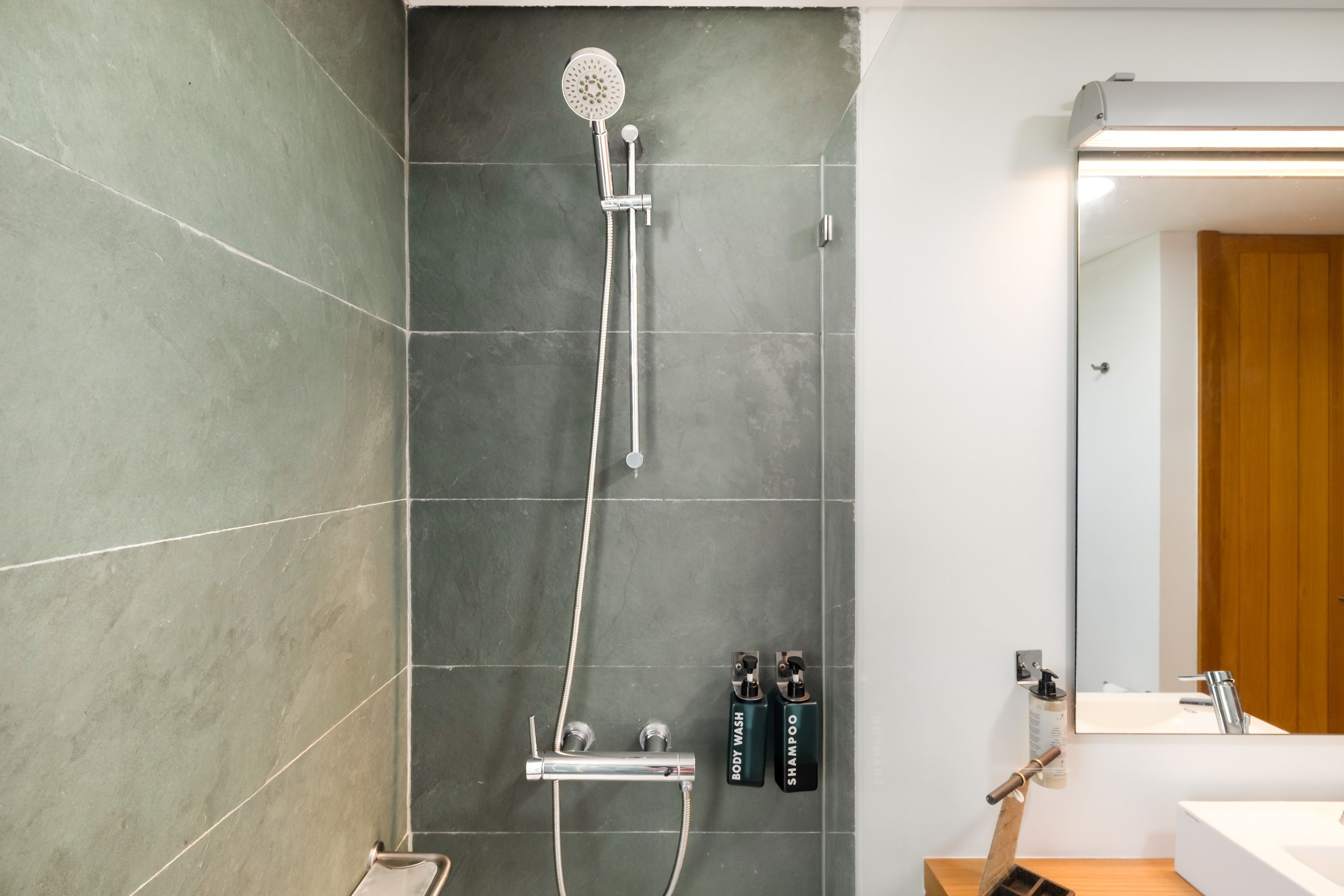 Un baño moderno con ducha, lavamanos y espejo.