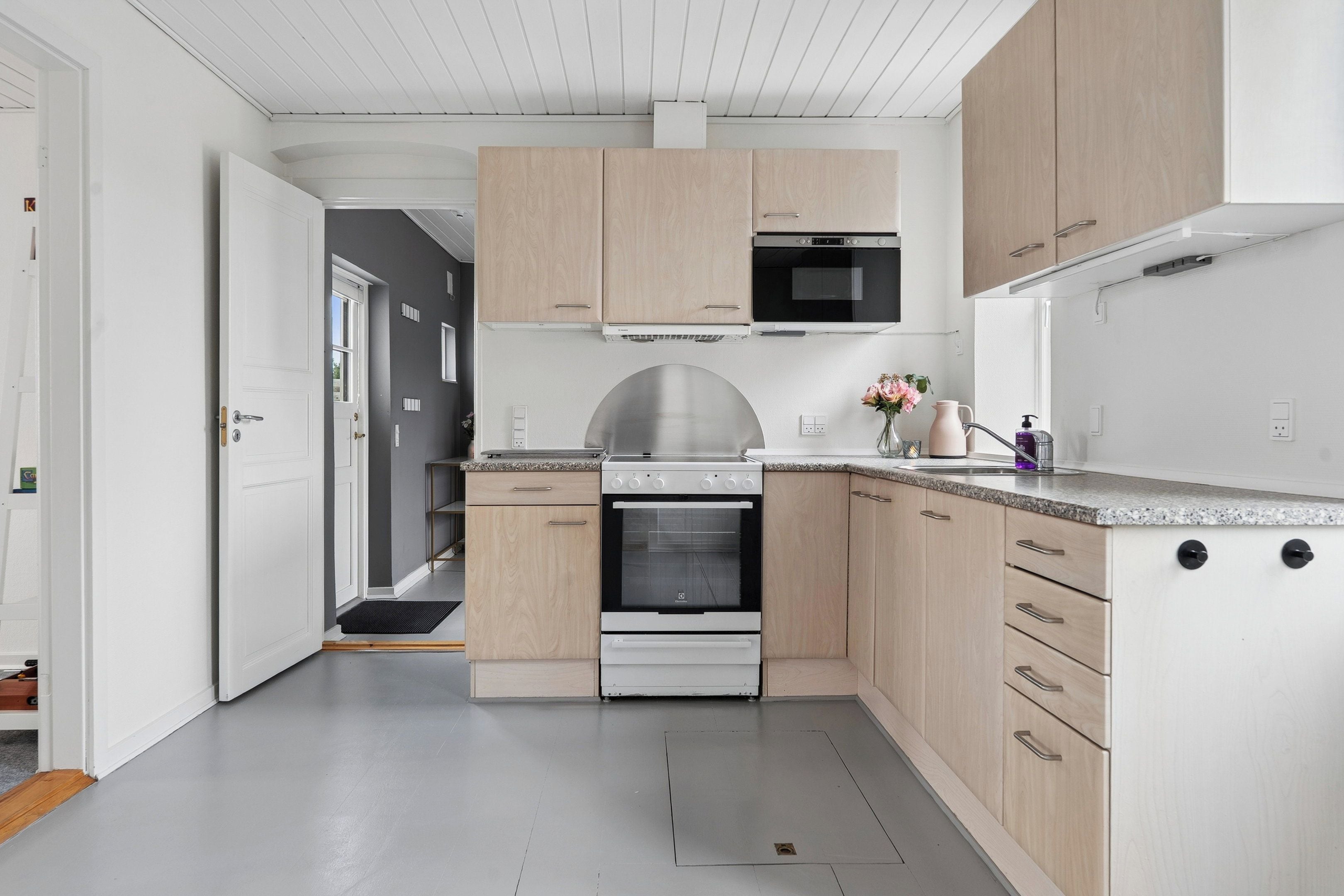 Een moderne keuken met een inbouwoven, magnetron en een roestvrijstalen afzuigkap.