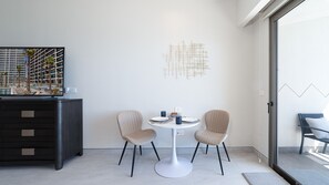 A modern hotel room with a dining area featuring two chairs and a round table, a dark wooden cabinet, and a large window overlooking a pool. - One 1402C Studio: Relaxing Oceanview Studio at Sonoran Star (Puerto Peñasco)