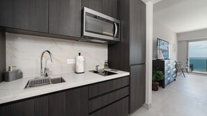 Cozinha moderna com micro-ondas embutido, pia e painel de fundo em mármore.