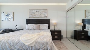 Quarto moderno com uma cama grande, mesas de cabeceira, um espelho e arte abstrata nas paredes.