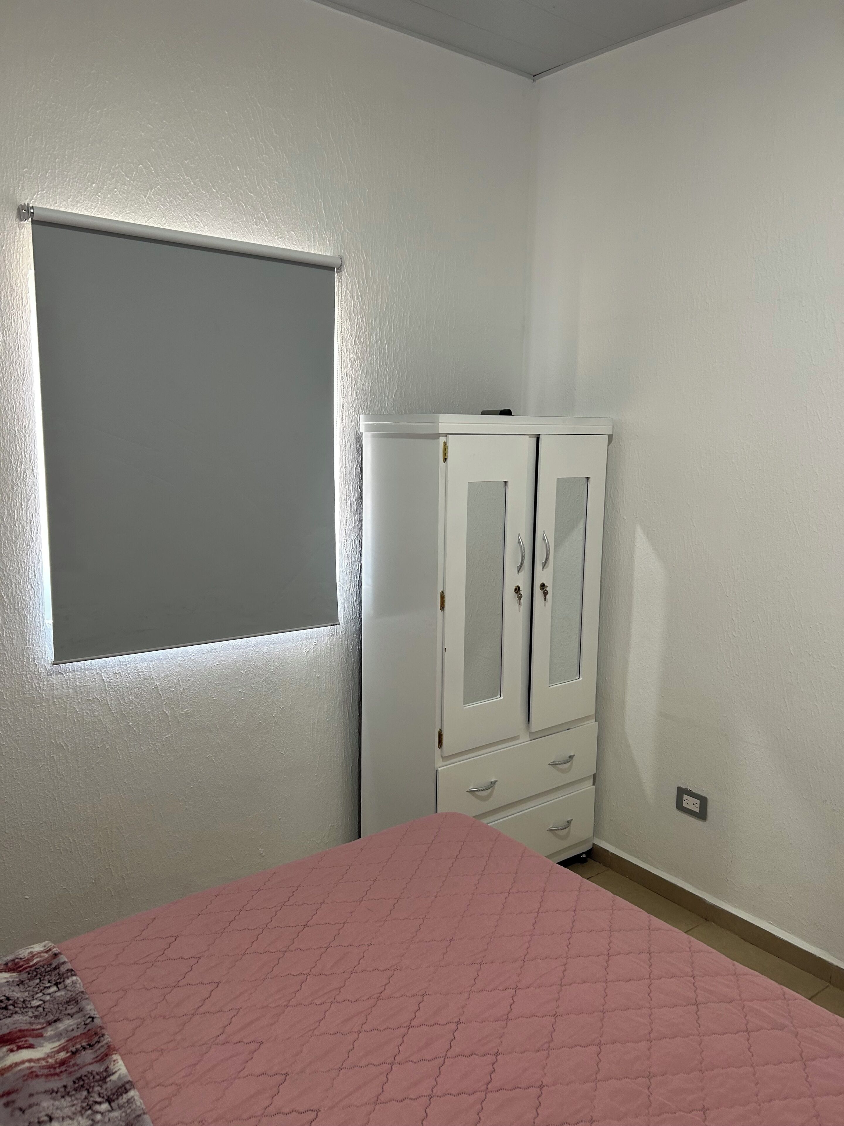 A room with a bed, a wardrobe, and a window.