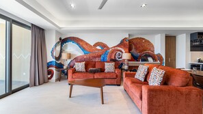 A modern living room with a large sofa, a coffee table, and a vibrant octopus mural on the wall. - One 1501 : The Sunset Suite (Puerto Peñasco)