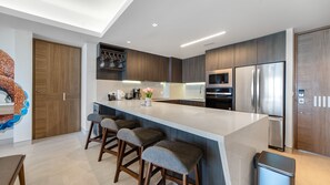 A modern kitchen with a central island, bar stools, built-in appliances, and a decorative vase. - One 1501 : The Sunset Suite (Puerto Peñasco)