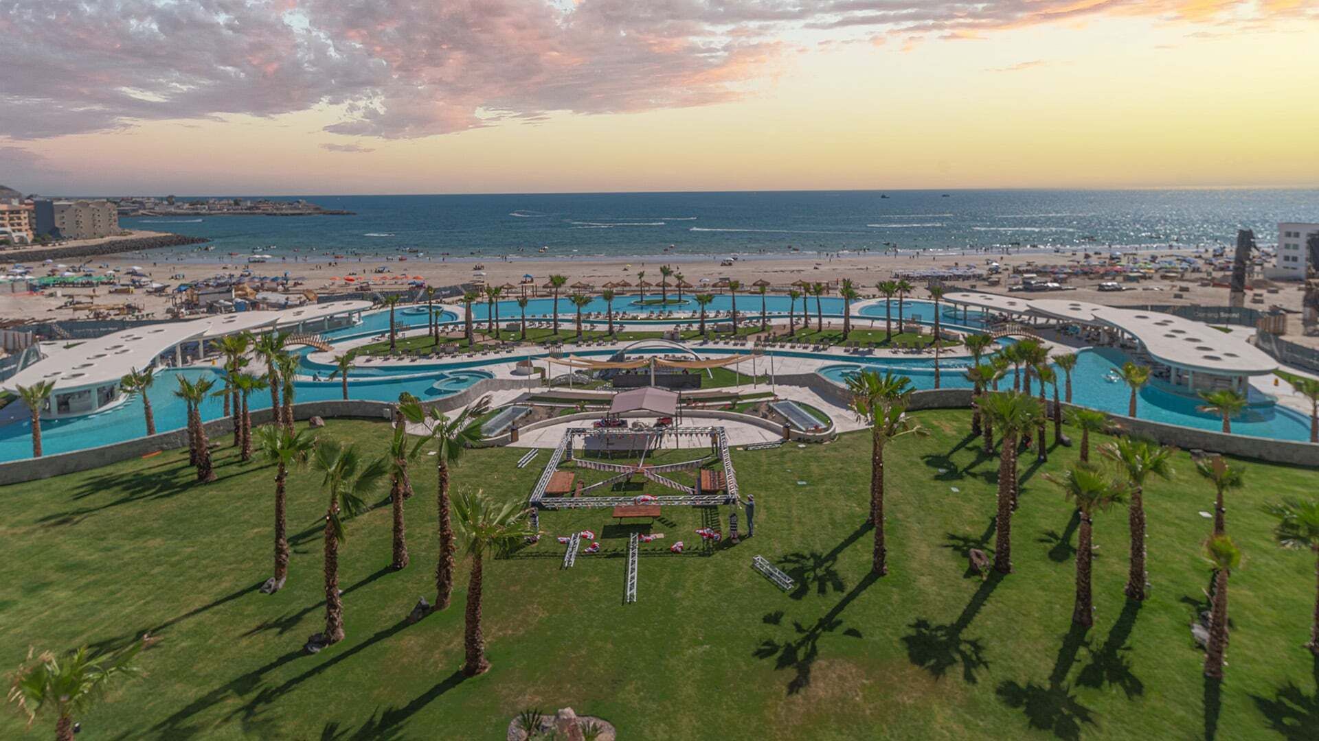 Een resort met meerdere zwembaden, een centraal plein en een strandgedeelte.