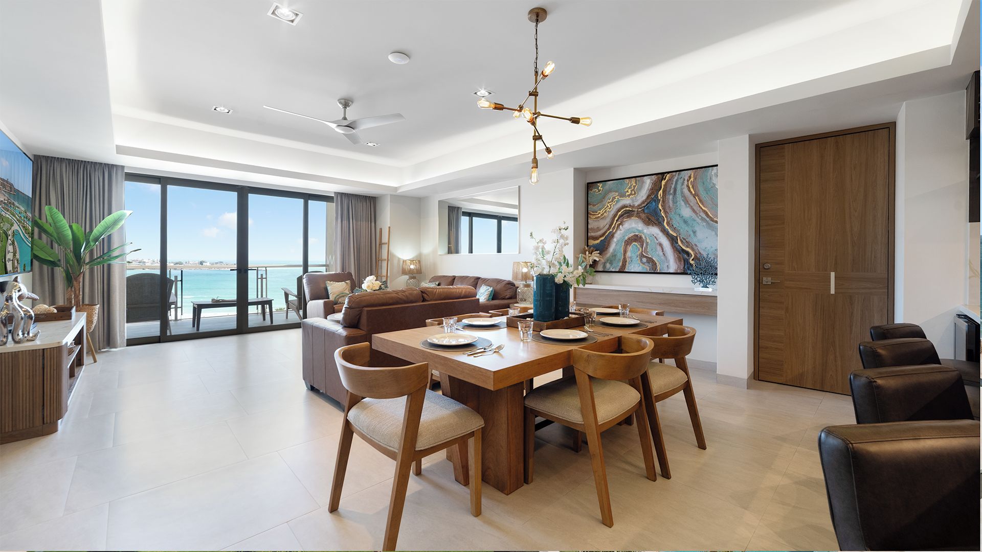 A modern living room with a dining area, large windows, and a view of the sea.
