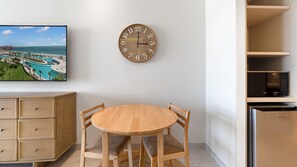 A modern kitchen with a round wooden table, a wall-mounted clock, and built-in appliances. - Two 501Full: The Ultimate Beachfront Getaway (Puerto Peñasco)