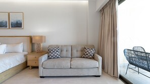 Ein modernes Schlafzimmer mit einem Bett, einem Sofa, einem Nachttisch, einer Lampe und einem Sessel.