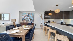 A modern kitchen with dark wood cabinets, a marble countertop, and pendant lighting. - One 101 : 👑 Azure Royale — upscale and memorable (Puerto Peñasco)