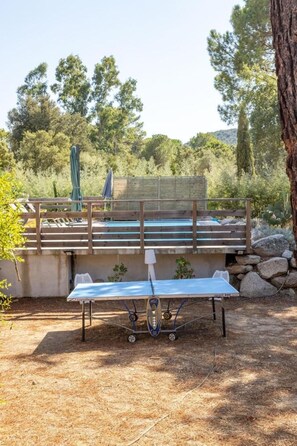 Un espace extérieur avec une piscine, une terrasse en bois, une table avec des chaises et une pergola.