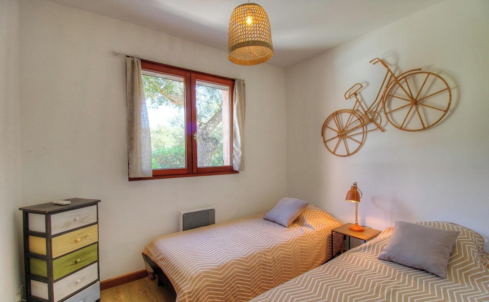 Een slaapkamer met een bed, nachtkastjes, een kaptafel, een raam met gordijnen en een fietsdecoratie aan de muur.