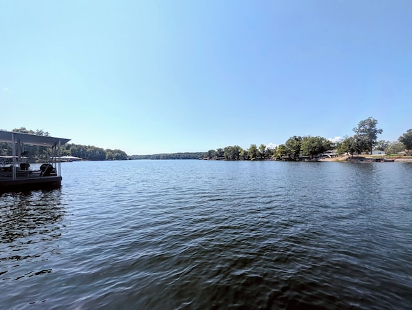A calm lake with a dock and a covered seating area.