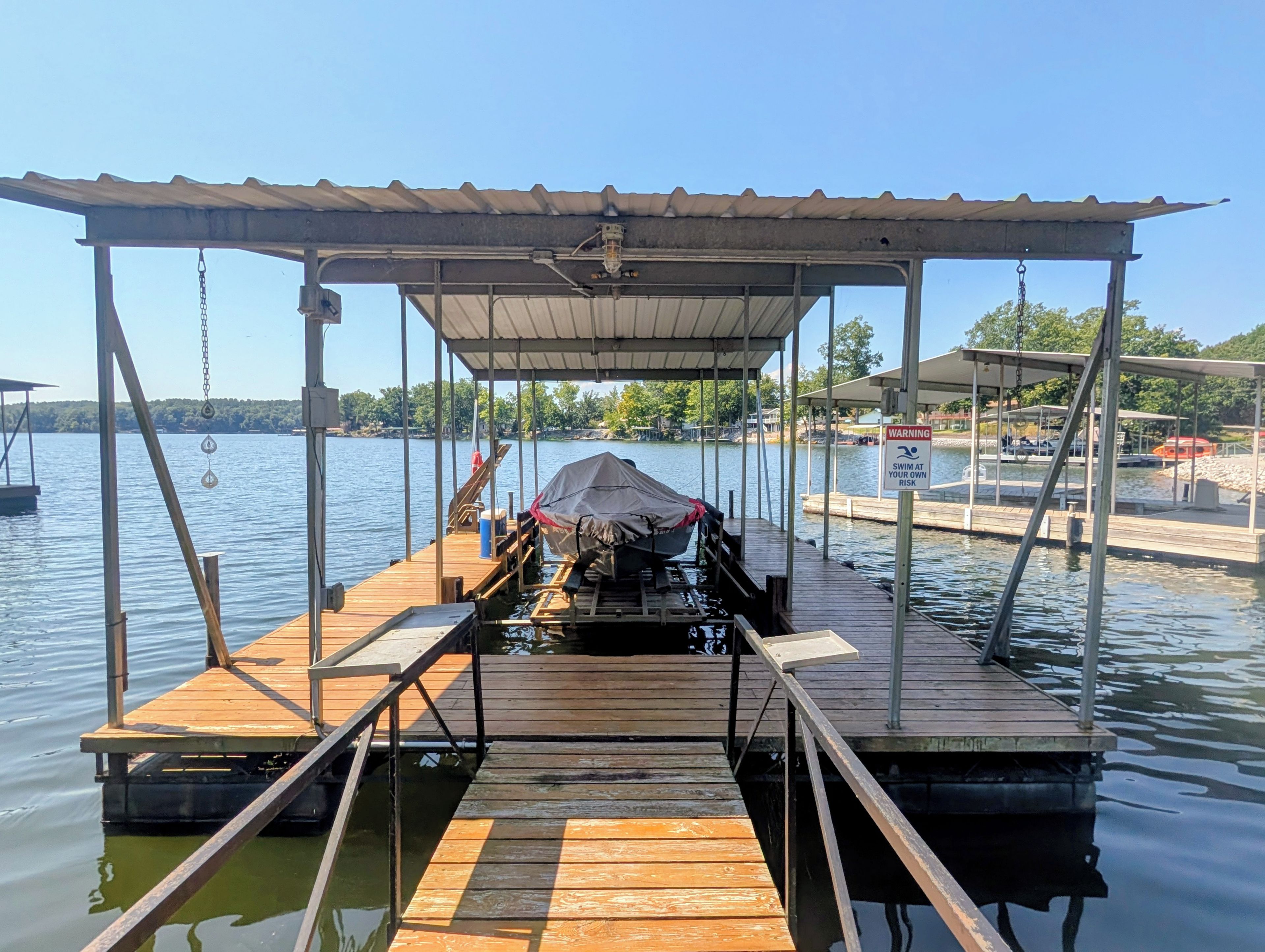 A wooden dock with a covered seating area and a warning sign.