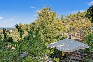 Eine Terrasse mit Tisch und Stühlen, umgeben von üppiger Vegetation und Blick aufs Meer.