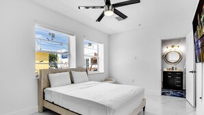 Quarto moderno com cama, ventilador de teto e vista para o exterior.
