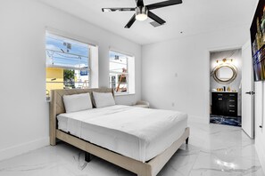 Een moderne slaapkamer met een bed, een plafondventilator en uitzicht op buiten.