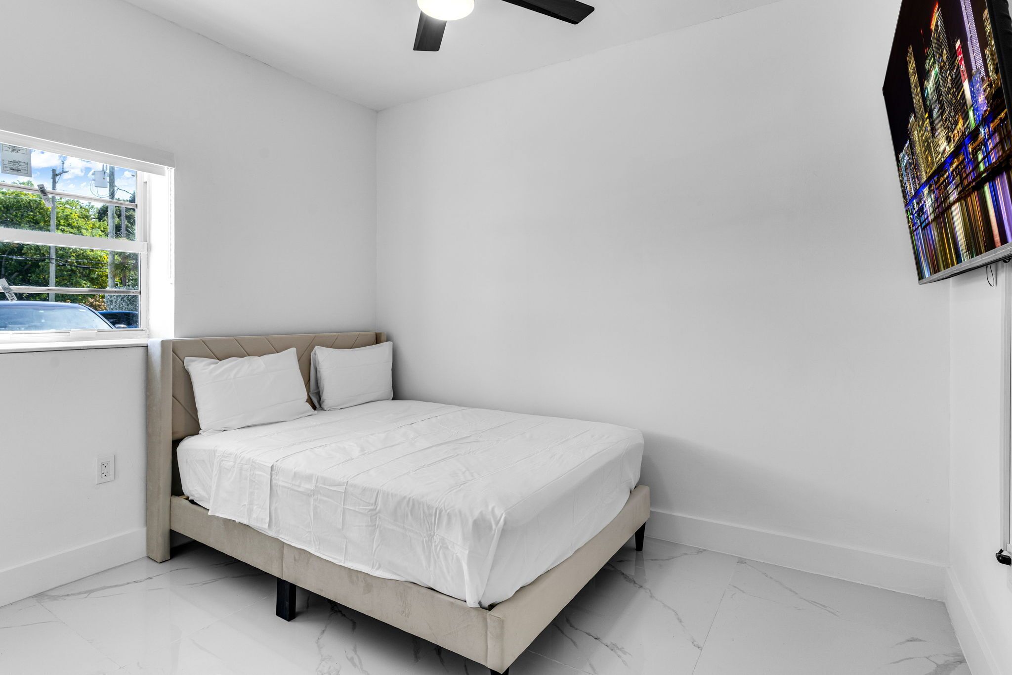 A bedroom with a bed, a window, and a ceiling fan.