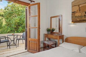 Ein Zimmer mit einem Bett, einem hölzernen Schreibtisch mit Spiegel, einem Stuhl und einem kleinen Tisch.