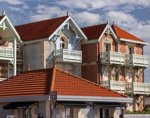 A building with multiple balconies, a covered entrance, and signs indicating a casual store and a French guest house. - Vrbo Property (LESPARRE MEDOC)