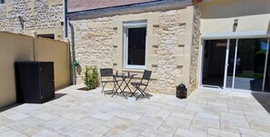 A stone building with a patio area featuring a table and chairs. - Vrbo Property (LESPARRE MEDOC)