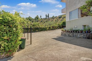 Ein gepflasterter Weg führt zu einem Gebäude mit einer Steinmauer und Blumentöpfen.