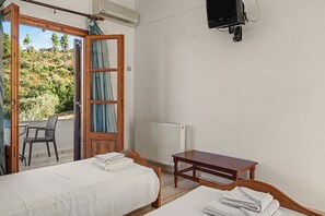 Ein Zimmer mit zwei Betten, einem Tisch, einem Stuhl und Blick ins Freie.