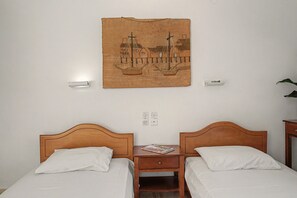 A hotel room with two wooden beds, a nightstand with a book, and a wall-mounted tapestry. - Room 'Orama  18' with Sea View, Wi-Fi and Air Conditioning (Εύβοια)