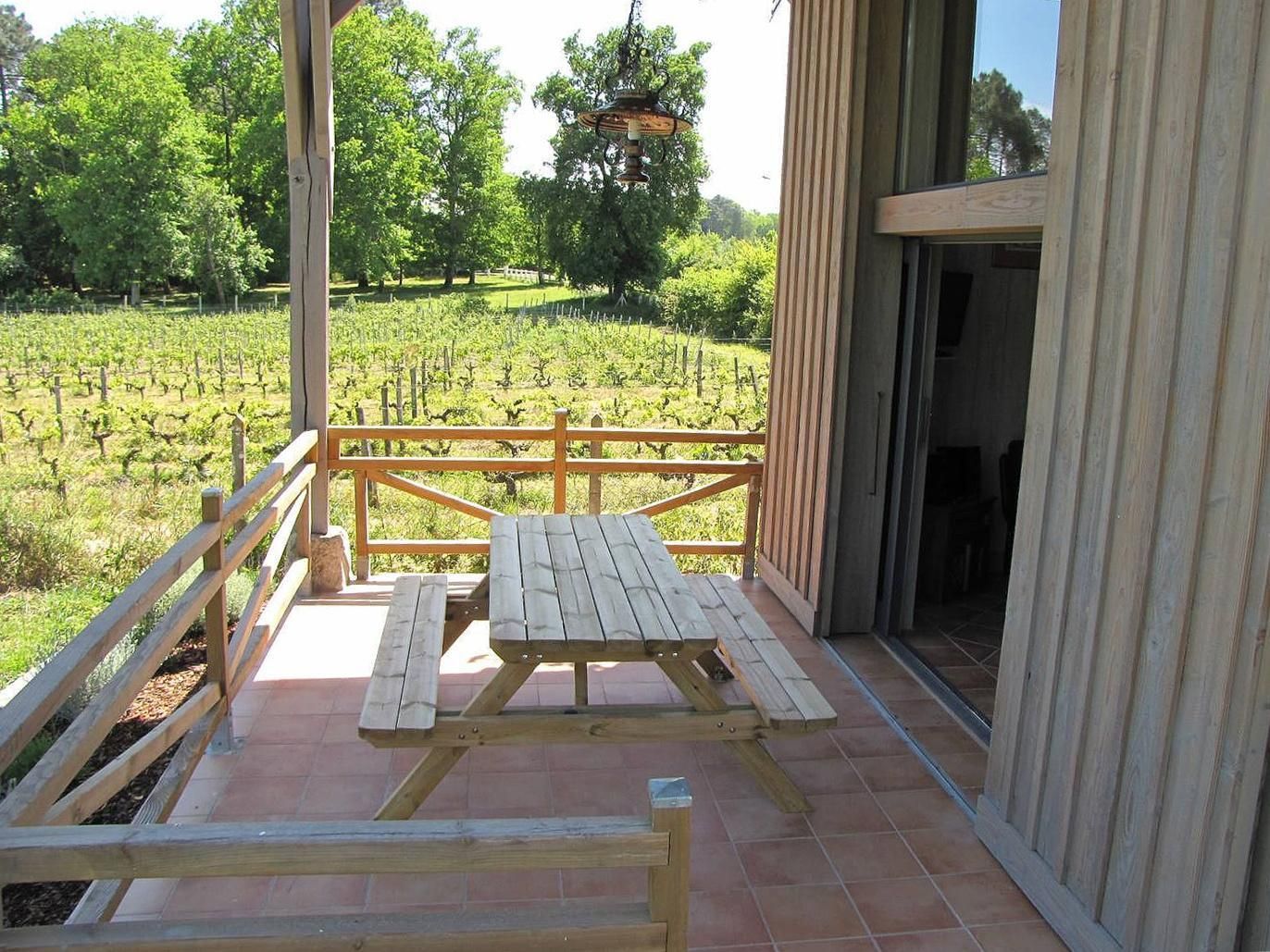 A wooden deck with picnic tables overlooking a vineyard.